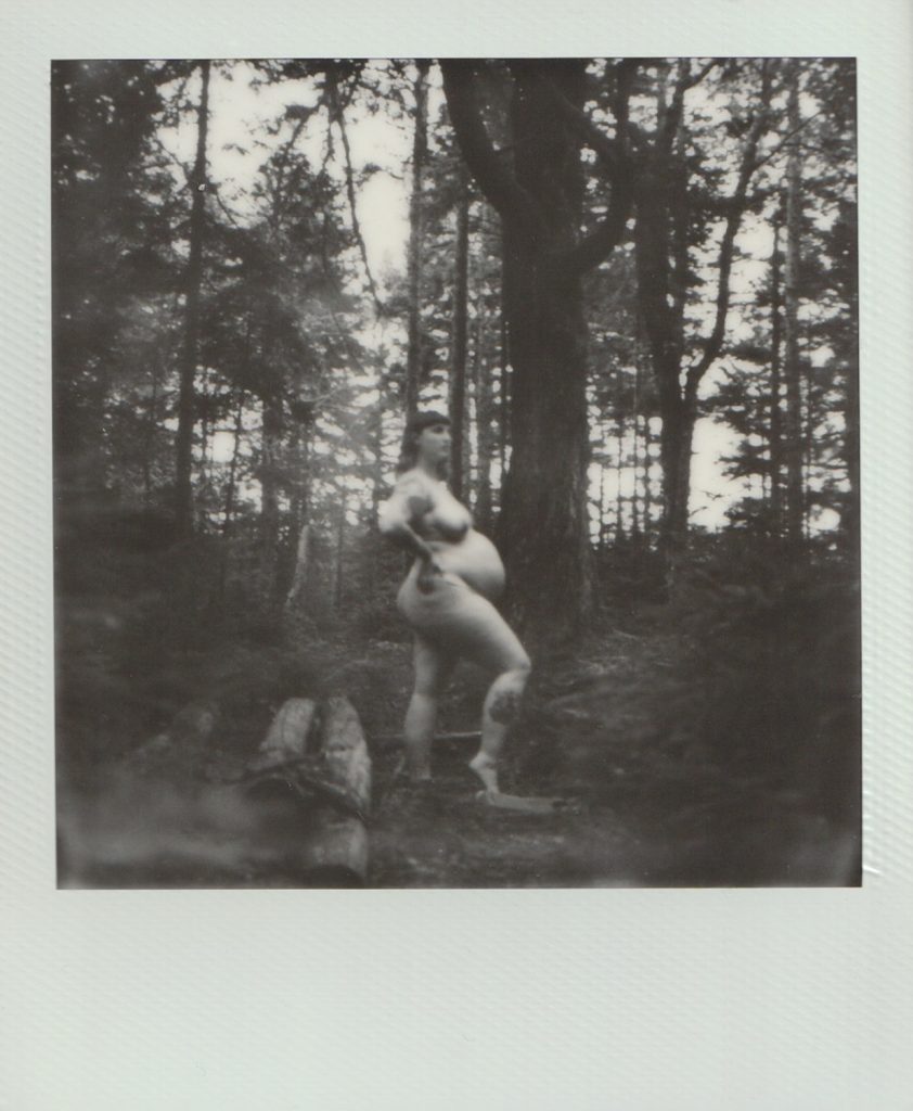 Polaroid Film of a pregnant woman standing naked in a forest.