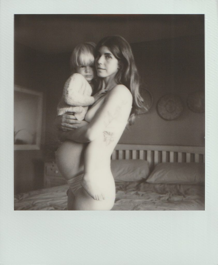 Polaroid film of a pregnant mother holding her eldest child.